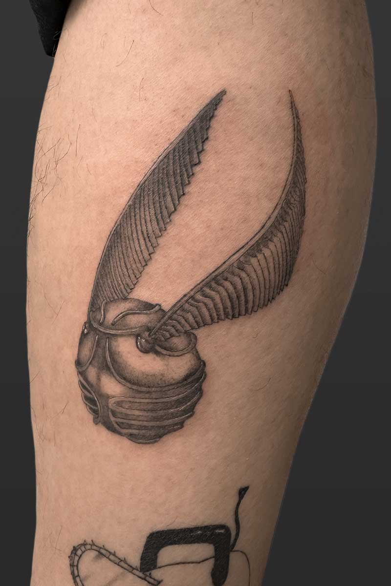 Legacy Tattoo| Black and grey, realism tattoo of the golden snitch from "Harry Potter"