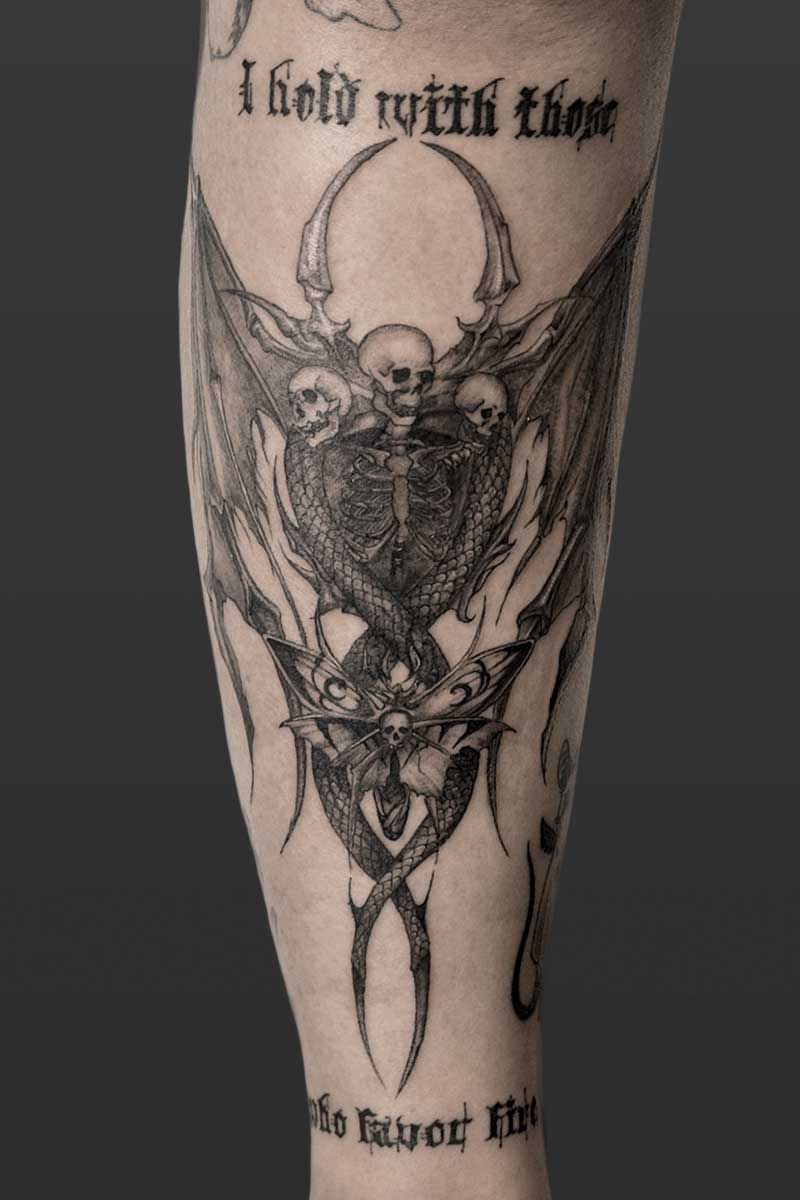 Legacy Tattoo| Black and grey tattoo of a skeleton with bat wings, horns, serpent body and a moth