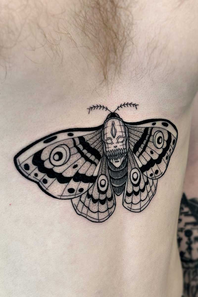 Legacy Tattoo| Black and grey tattoo of a moth with a face on it's back