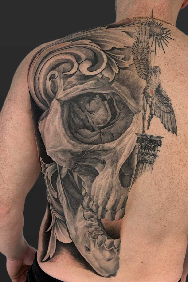 Legacy Tattoo| Black and grey, realism tattoo of half of a skull's face and Icarus reaching towards the sun while standing on a pillar