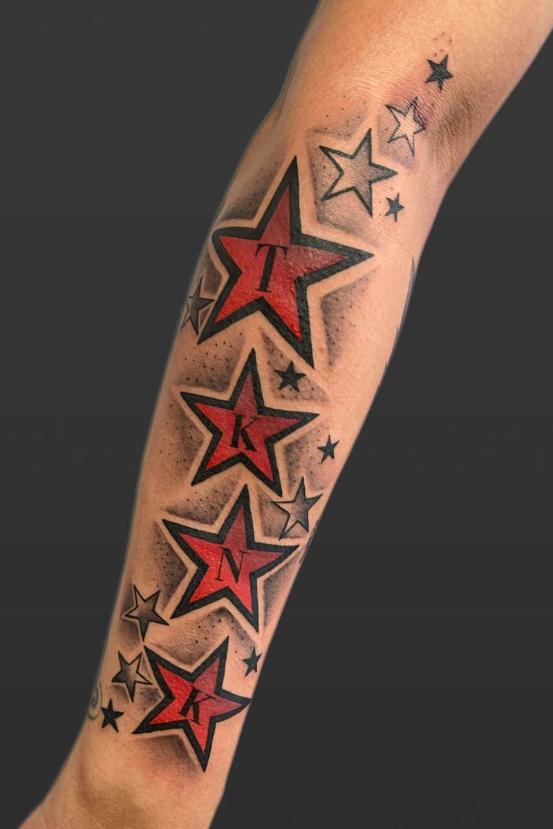 Legacy Tattoo| Tattoo of five red and black stars with several black and grey stars around them