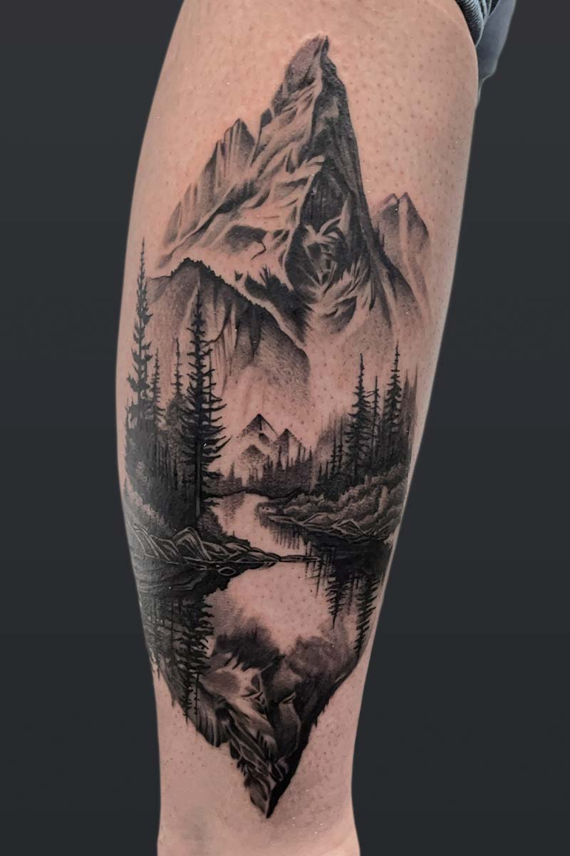 Legacy Tattoo| Black and grey, realism tattoo of a mountain range with forest and river