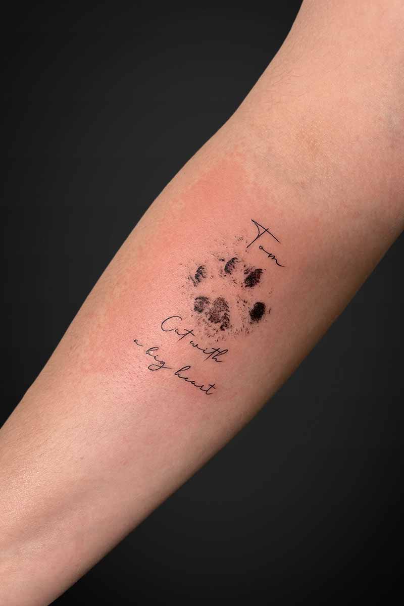 Legacy Tattoo| Fineline, script tattoo of a cat's paw, name and a quote