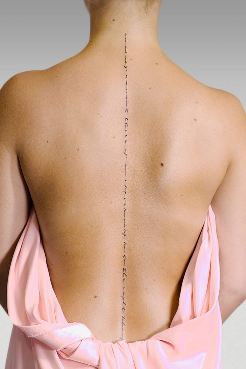 Legacy Tattoo| Fineline, script tattoo of words centre down the client's back