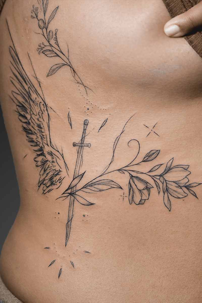Legacy Tattoo| Fineline tattoo of an angel wing, sword and flowers