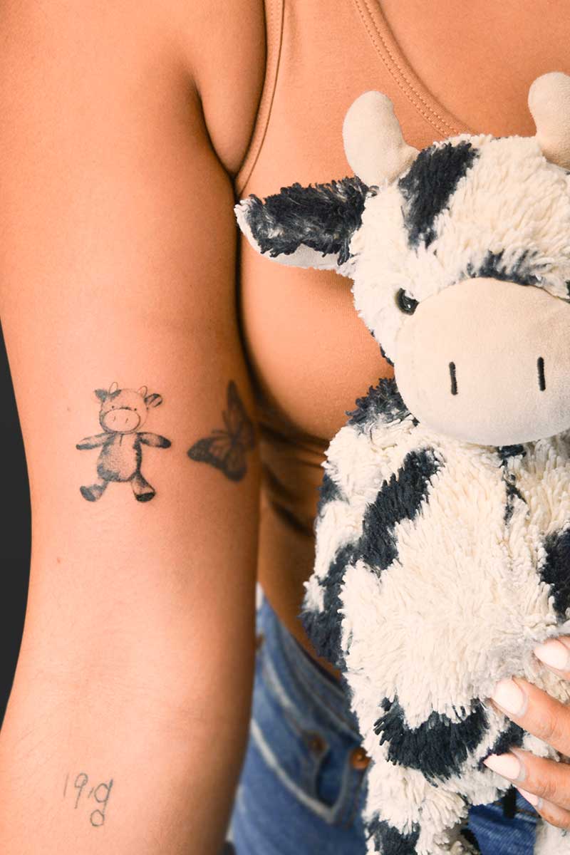 Legacy Tattoo| Black and grey, realism tattoo of a cow stuffed toy