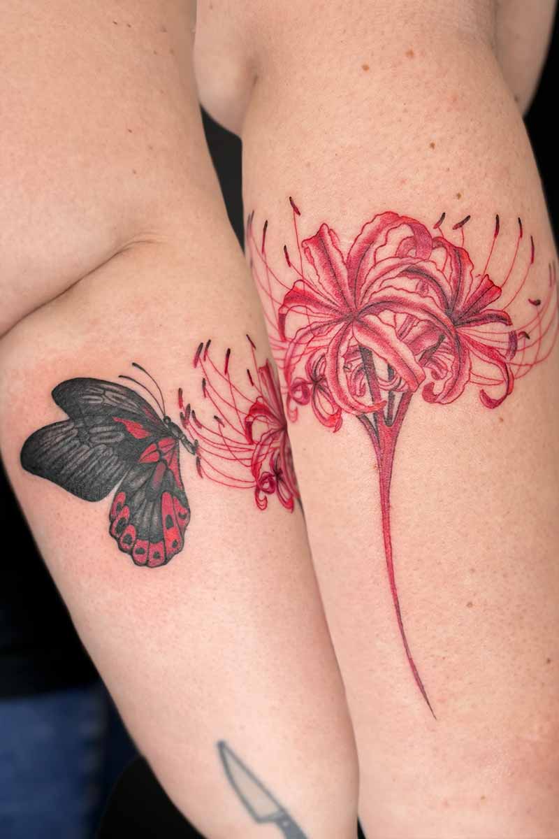 Legacy Tattoo| Floral tattoo of a black and red butterfly and red spider lily