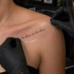 Tattoo artist in black gloves peeling a transfer stencil off a client’s collarbone at Legacy Tattoo in Calgary