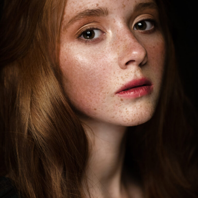 Young red-haired woman with freckles looking at the camera.